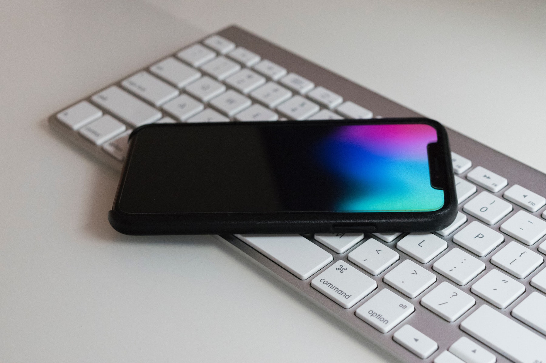 Photo d'un iPhone posé sur un clavier d'ordinateur, deux éléments essentiels pour booster son compte Instagram