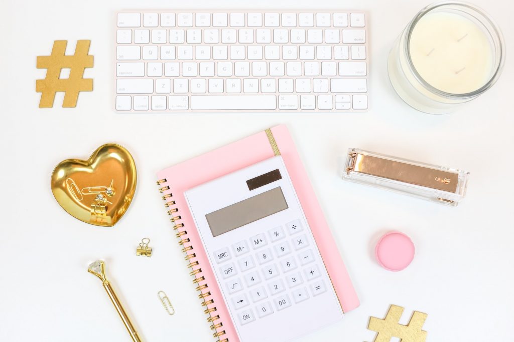 Photographie d'une calculatrice blanche sur un calepin rose permettant de calculer avec précision son taux d'engagement sur Instagram