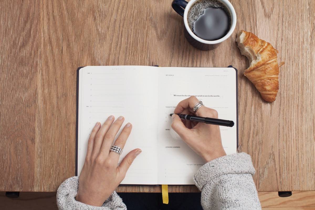 Carnet ouvert sur une page d’objectifs, à côté d’un café, pour définir son objectif avant de créer un compte Instagram